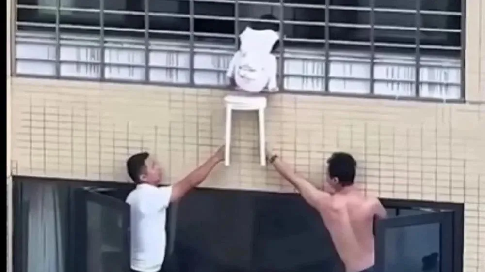 Uma menina ficou pendurada do lado de fora da janela de um prédio, a dezenas de metros de altura.